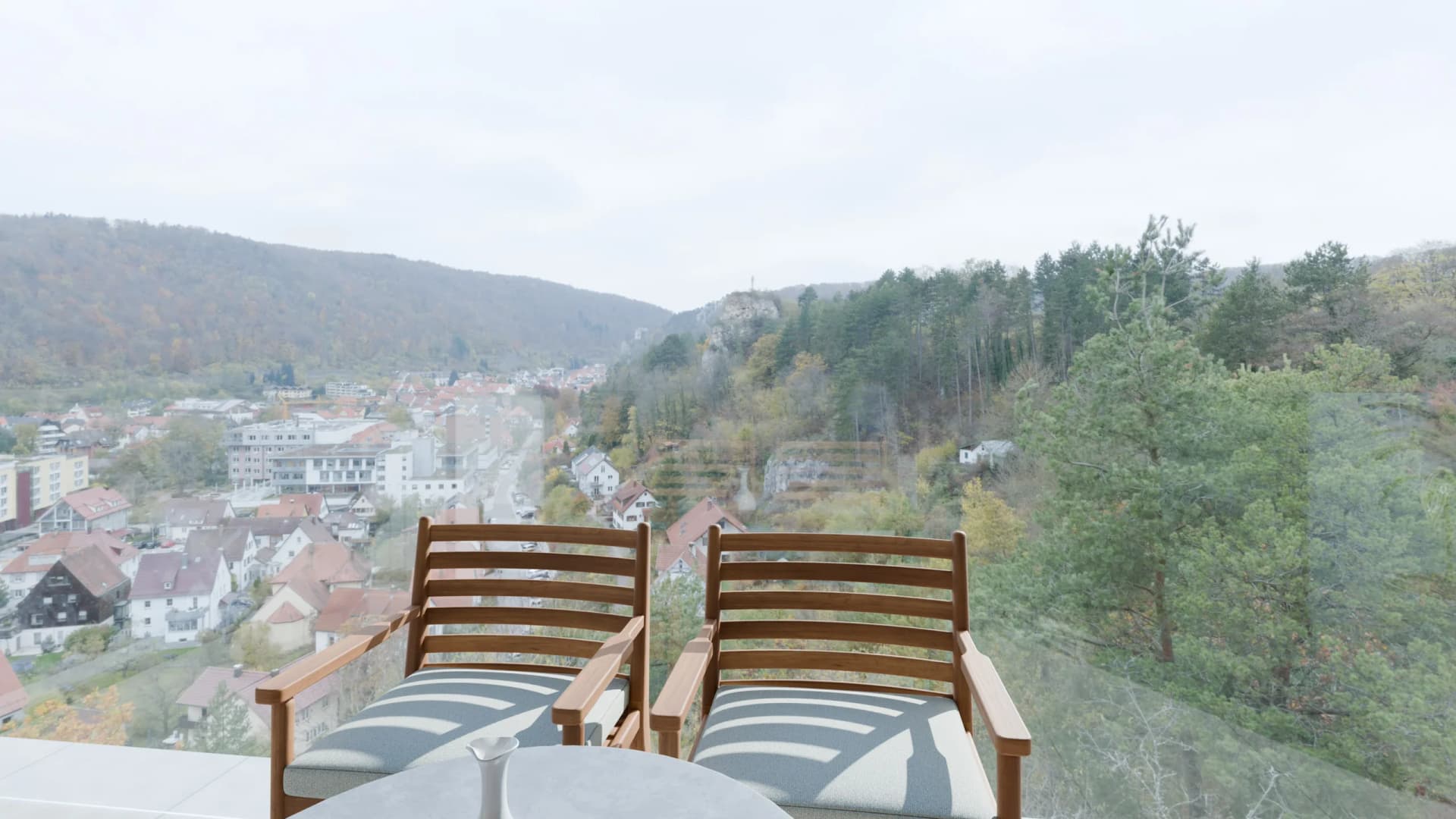 The flat's glazed terrace at midday, two armchairs and the valley beyond the railing